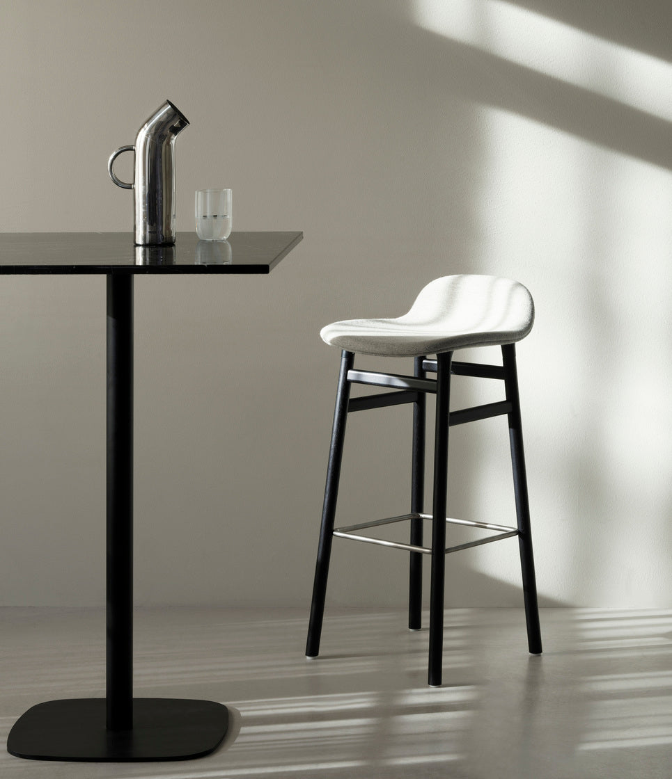 Hocker forms of light gray with a black oak base
