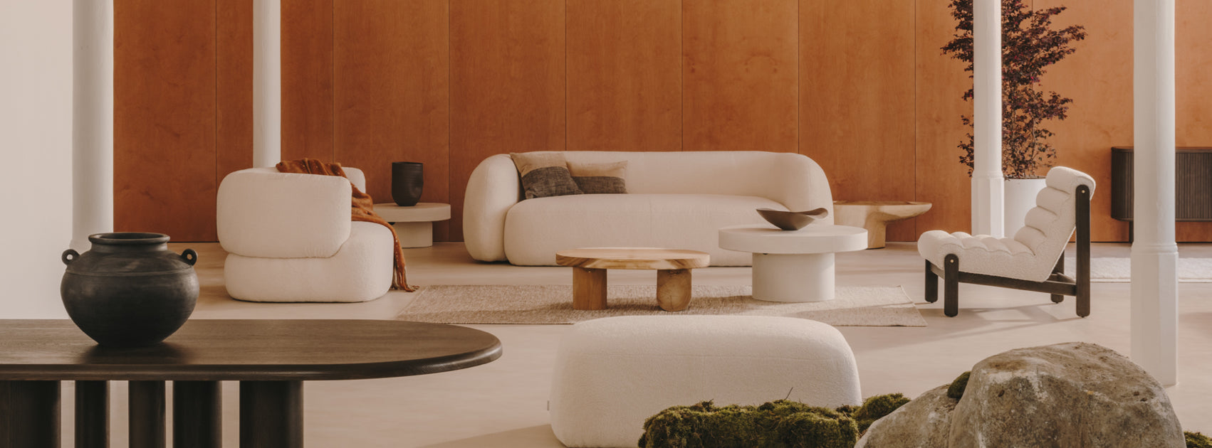 Grafika przedstawia salon urządzony w stylu modern classic z domieszką japandi. Ściana została wykończona materiałem przypominającym drewno, natomiast meble są utrzymane w beżowej i minimalistycznej stylistyce.