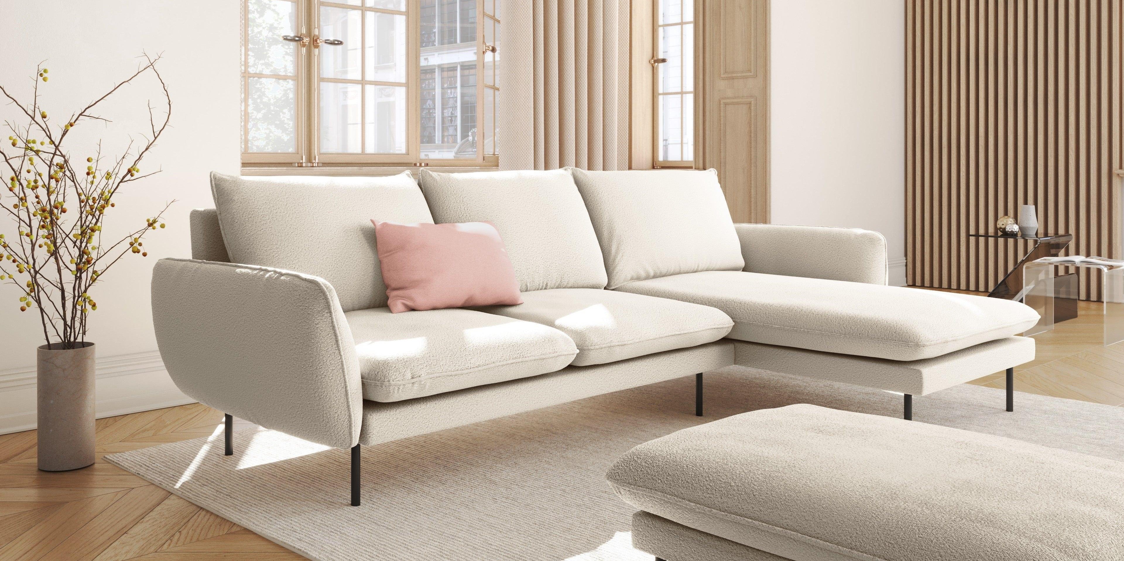 W salonie znajduje się minimalistyczny narożnik w kolorze białym, ozdobiony różowymi poduszkami.