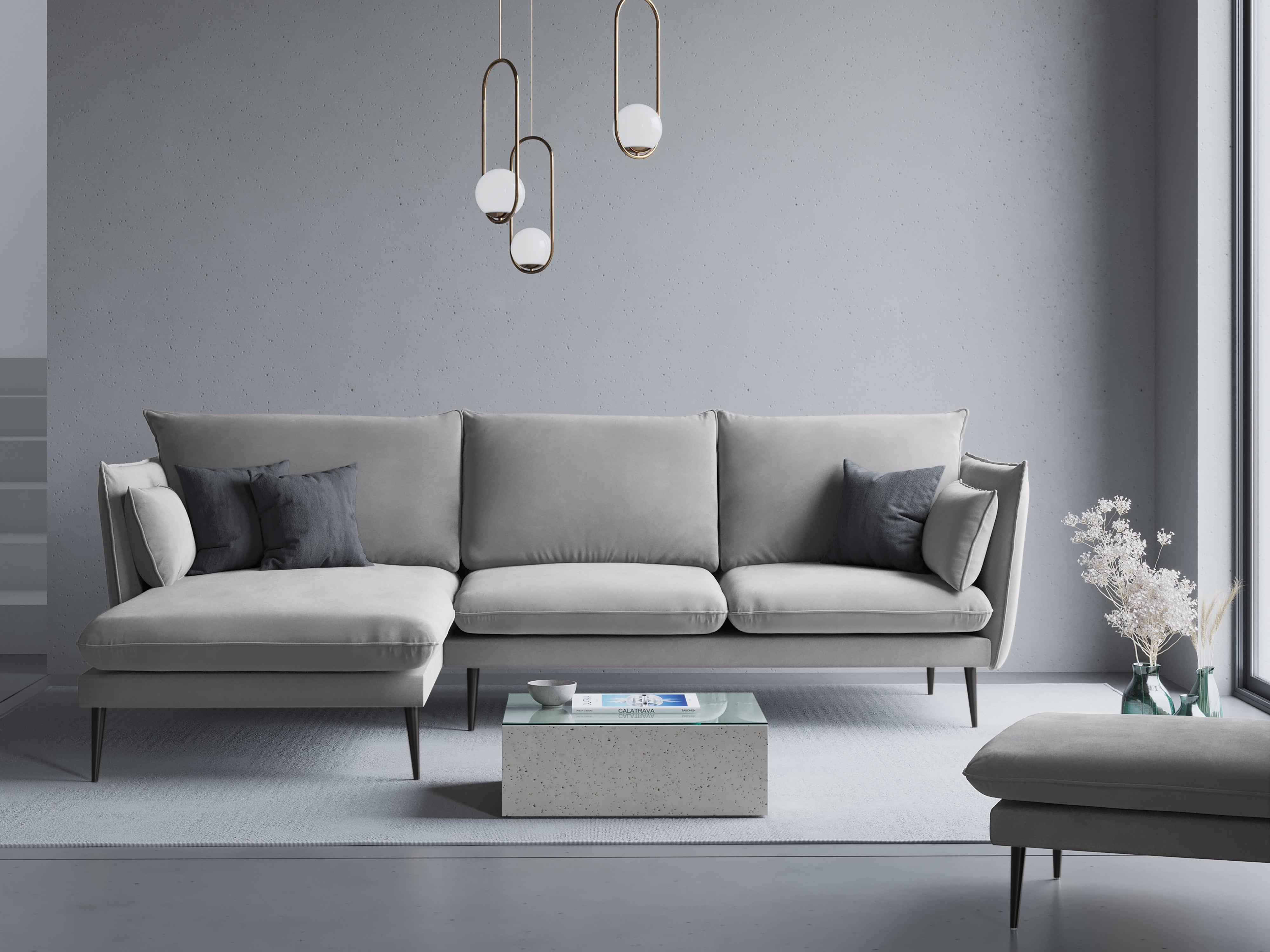 Szara minimalistyczna sofa umieszczona w szarej, monotematycznej przestrzeni. Przed sofą znajduje się stolik kawowy. 