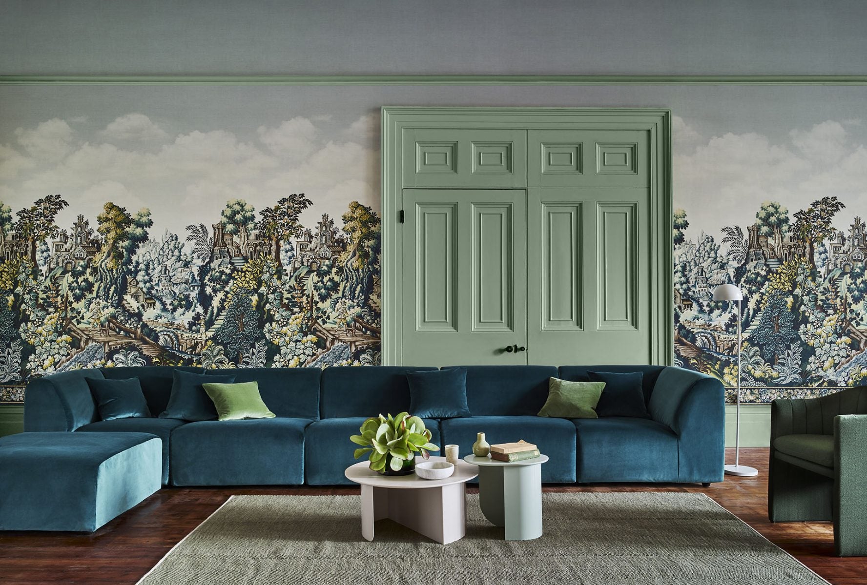 Na zdjęciu znajduje się różowy parawan, przed którym stoi różowy, pikowany fotel. Na ścianie znajduje się tapeta przedstawiająca malowniczy ogród.