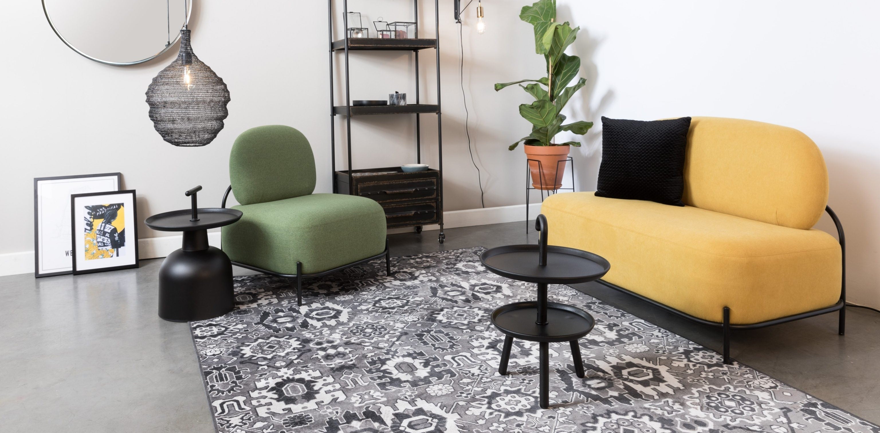 Eklektyczny salon, w którym znajduje się niewielka żółta sofa oraz niebieski fotel. Na podłodze położone wzorzysty, czarno-biały dywan.