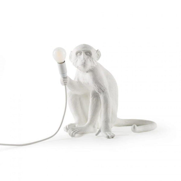 Monkey Sitting to lampa stołowa stworzona z myślą o miłośnikach stylu awangardowego. Przykuwający wzrok kształt oraz ponadczasowa kolorystyka odnajdą się w wielu domowych pomieszczeniach. A swoim ekscentrycznym kształtem dopełnią każdy salon i sypialnię. Wykonana została w całości z żywicy organicznej. Dołączona do zestawu żarówka pomoże w stworzeniu przytulnej atmosfery. Dodatkowo wprowadzi w elegancki sposób nutkę humoru do wnętrz.
